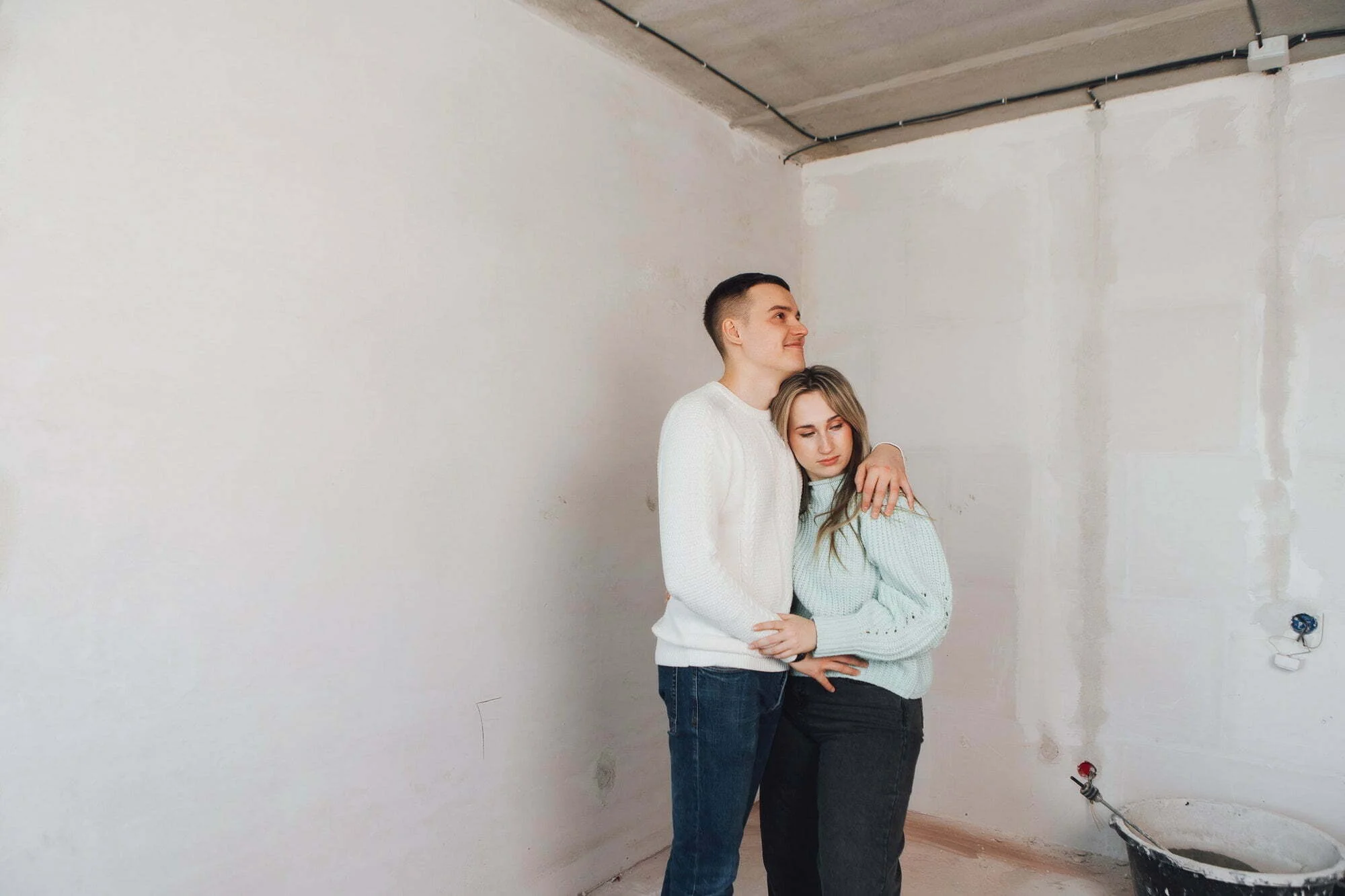 Couple in unfinished building. Woman and men thinking about apartment renovation